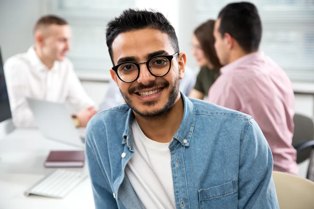 Colaborador latino con aud&iacute;fonos concentrado en laptop, adapt&aacute;ndose a distintas din&aacute;micas